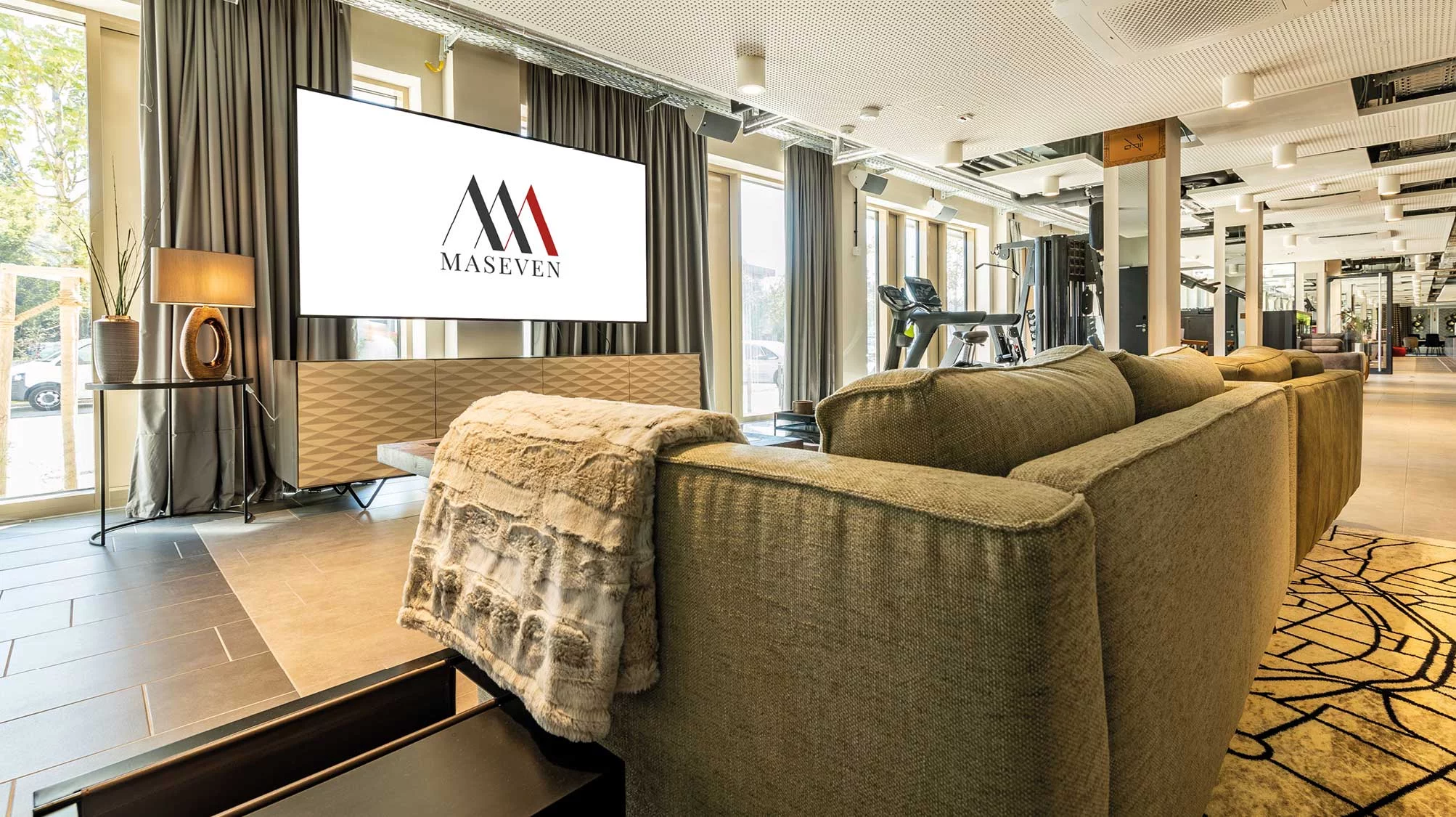 Ein Sofa vor einem Fernsehen im Messe Hotel München MASEVEN am Standort Dornach